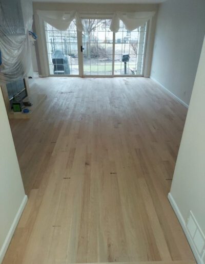 A living room with hardwood floors being refinished.