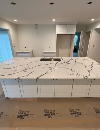 A kitchen with a white marble island under construction.
