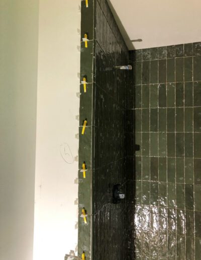 A green tiled shower is being remodeled.