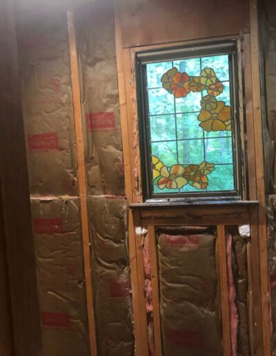 A bathroom is being remodeled with a stained glass window.