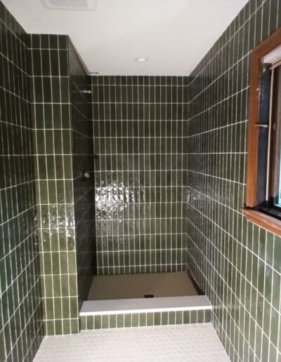 A bathroom with green tiled walls and a window.