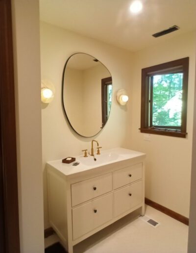 A bathroom with a white vanity and a round mirror.