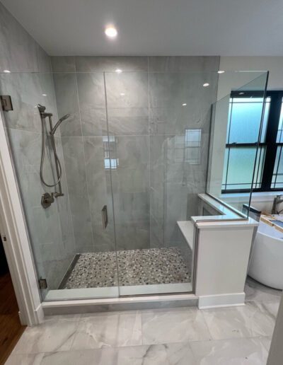 A bathroom with a glass shower stall and a tub.