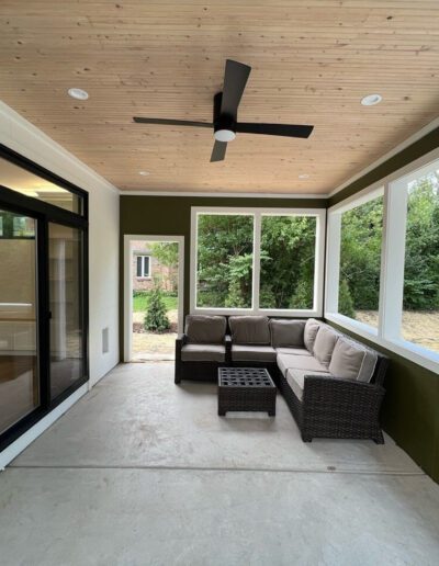 A screened in porch with a ceiling fan and sliding glass doors.