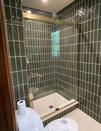A green tiled bathroom with a glass shower door.