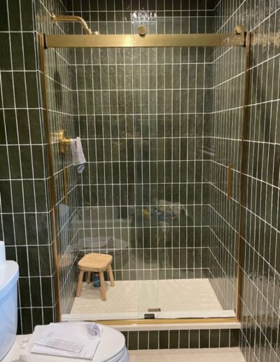 A green tiled bathroom with a glass shower door.