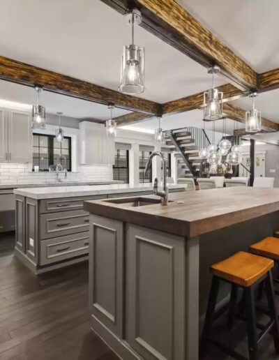A large kitchen with wood beams and stools.