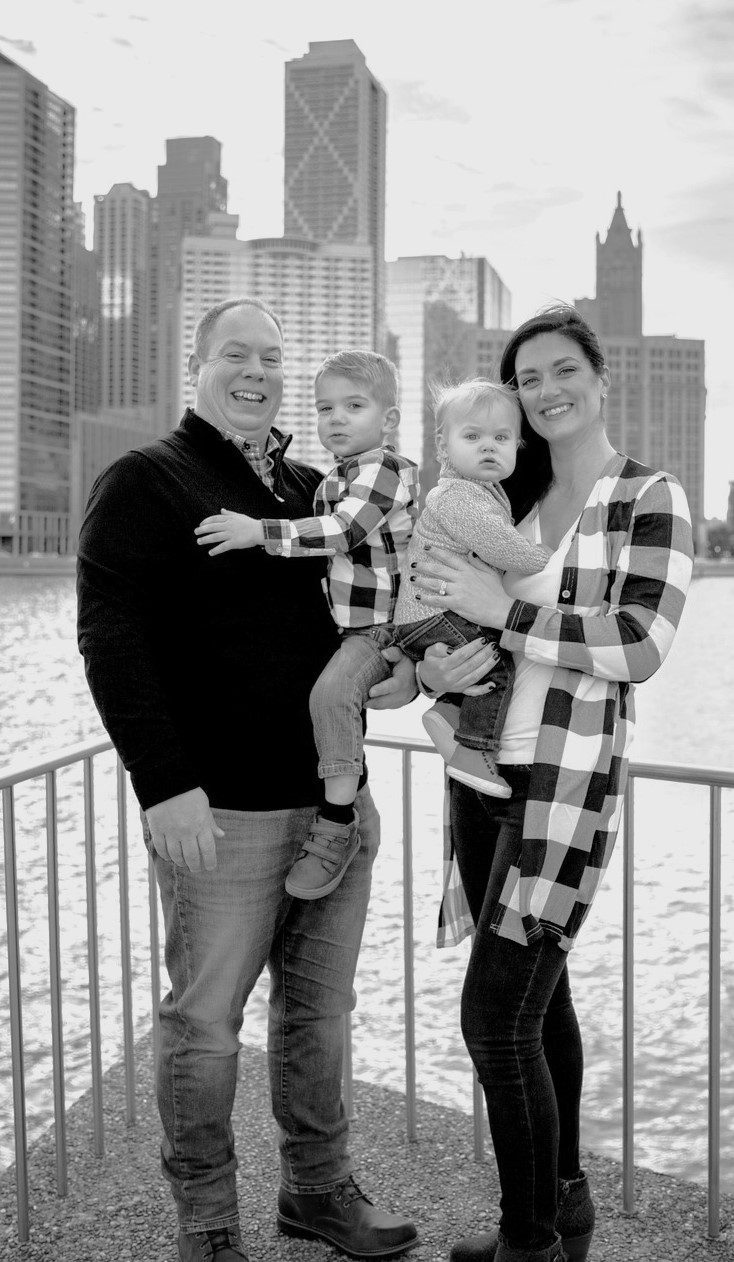 A black and white photo of a family posing in front of a city skyline.