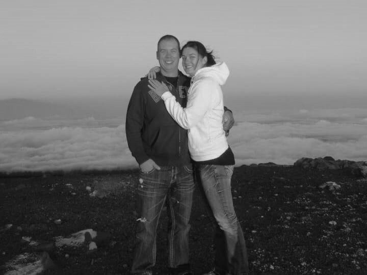 A black and white photo of a couple on top of a mountain.